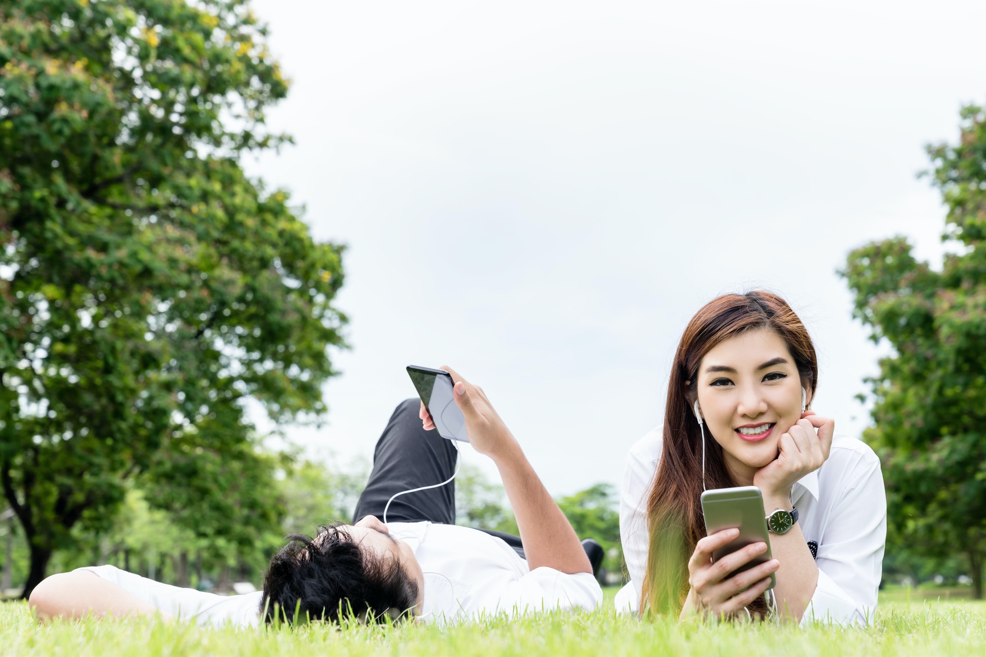 Asian couple or lover lay down holding earphone, smartphone